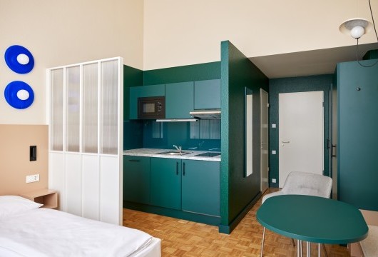 Modernes Apartment mit einer Küchenzeile, einem Tisch und Bett – stilvolles Wohnen auf Zeit Hannover in durchdachtem Design