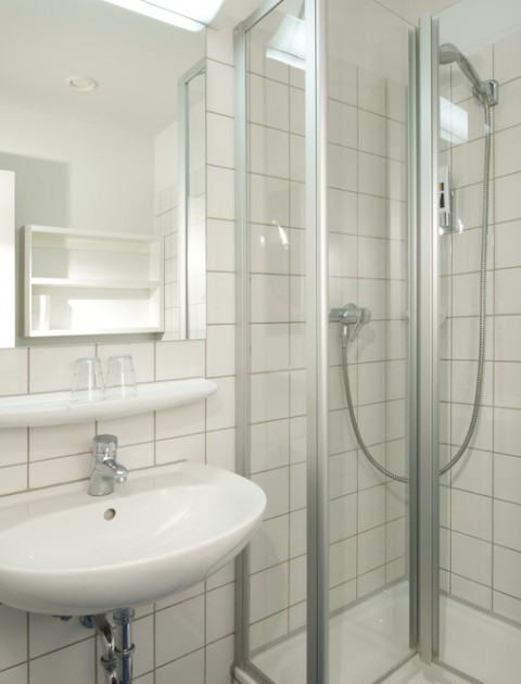 Ein modernes Bad mit Dusche, Waschbecken und Spiegel in einem möblierten Apartment in Hannover