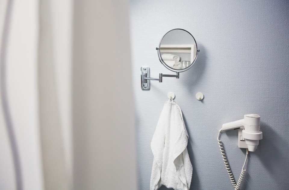 Ein Badezimmerdetail mit einem Handtuch, Vergrößerungsspiegel und Föhn im möblierten Zimmer in Hannover
