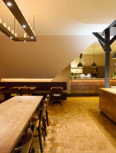 Ein einladender Essbereich mit stilvoller Beleuchtung in der Talking Kitchen Hannover, mit hölzernen Tischen und Stühlen