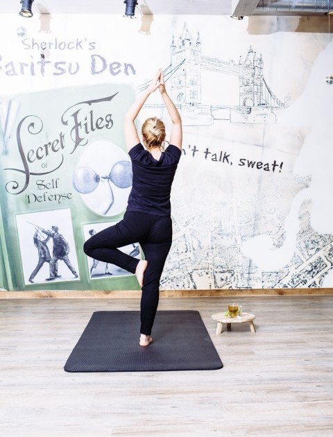 Das Bild zeigt eine Frau im Fitnessraum beim Praktizieren von Yoga.