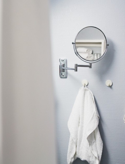 Ein Badezimmerdetail mit einem Handtuch, Vergrößerungsspiegel und Föhn in einem möbilierten Apartment in Hannover
